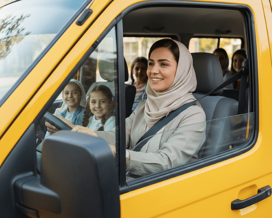 پیشنهاد: یک نمای بیرونی از یک ون سرویس مدرسه تمیز و مرتب در حال حرکت آرام در یک خیابان شهر (شلوغ نباشد). یا نمایی از داشبورد خودرو که راننده زن (دست‌هایش روی فرمان) با دقت به مسیر نگاه می‌کند و کنار او یک تبلت با نقشه مسیر دیده شود.
